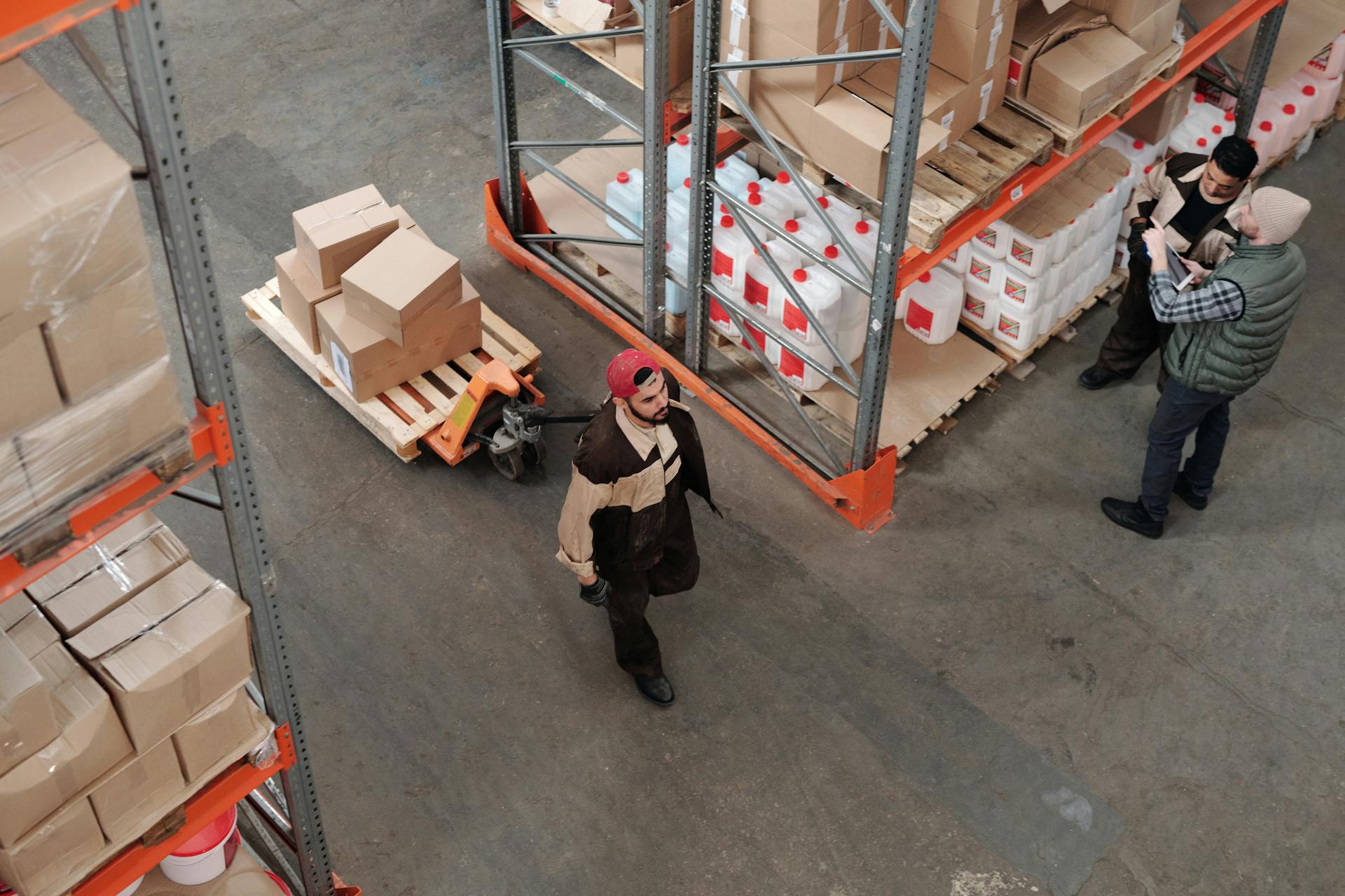 A worker completing the pick and pack fulfillment process by carrying recently packed boxes to a truck on a hydraulic jack.
