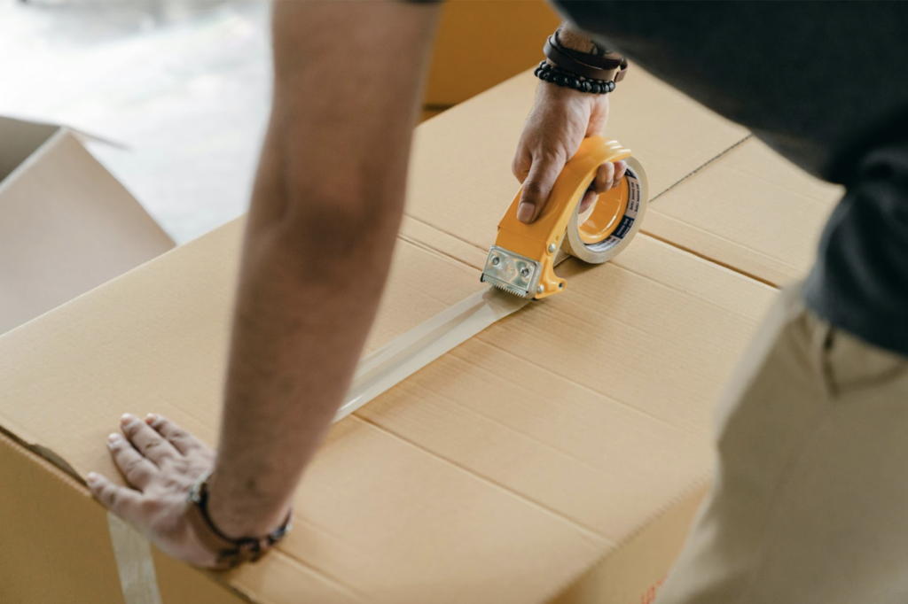 Person taping a box shut as a part of the pick and pack fulfillment process.