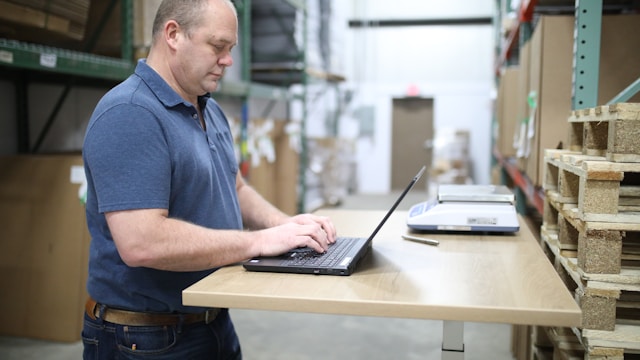 A man in a warehouse using his laptop.