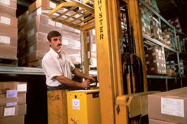 A man operating a yellow warehouse forklift.