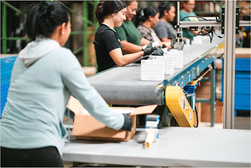 Women kitting items in a warehouse.