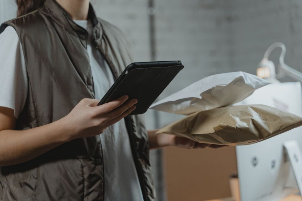 A person holding a black tablet and packages