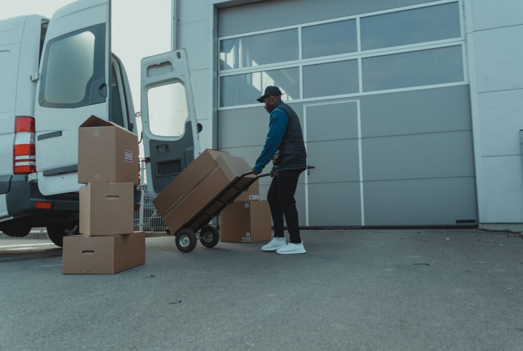 A man pulling a trolley with delivery boxes